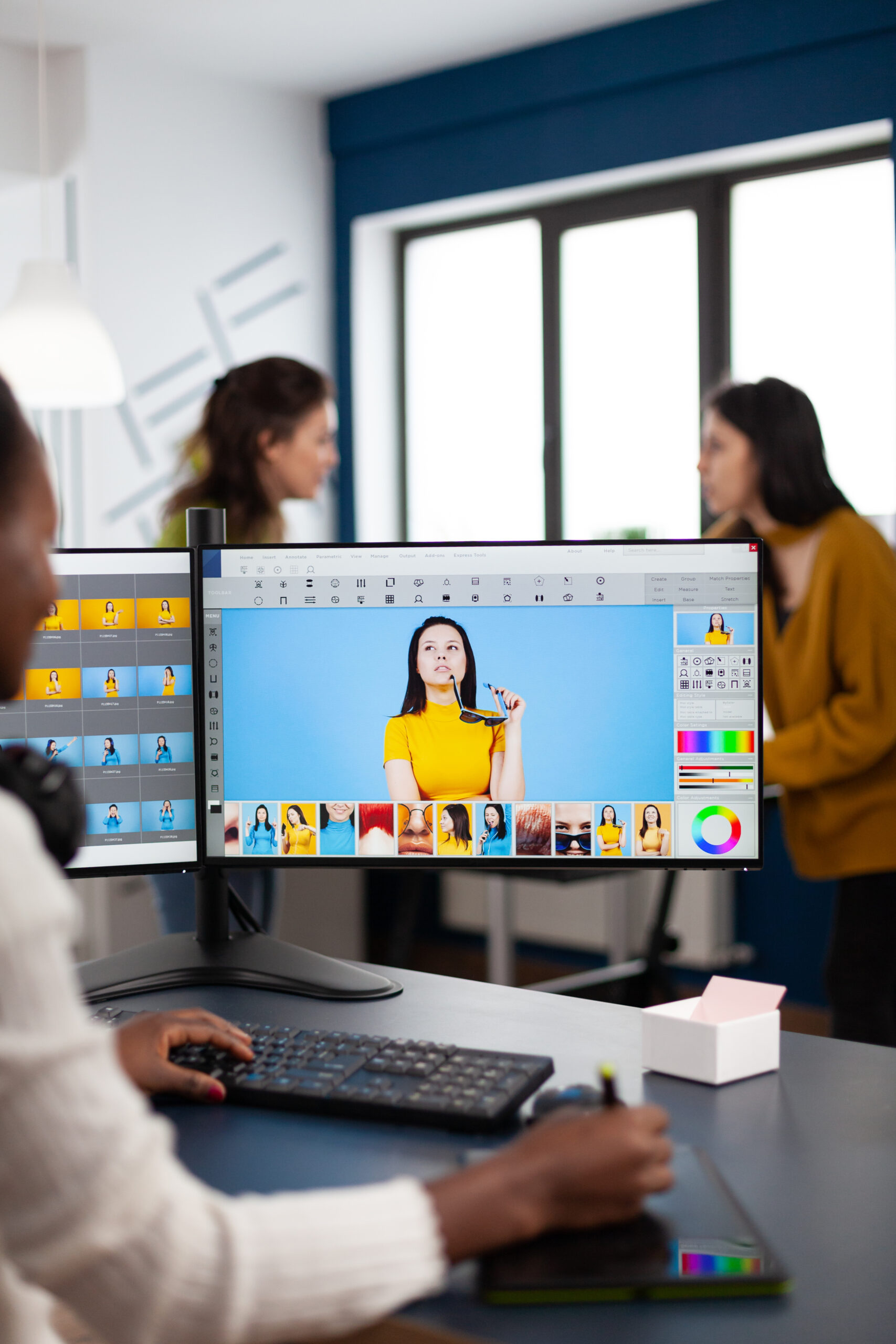 Black retoucher artist analysing images on pc with two monitors